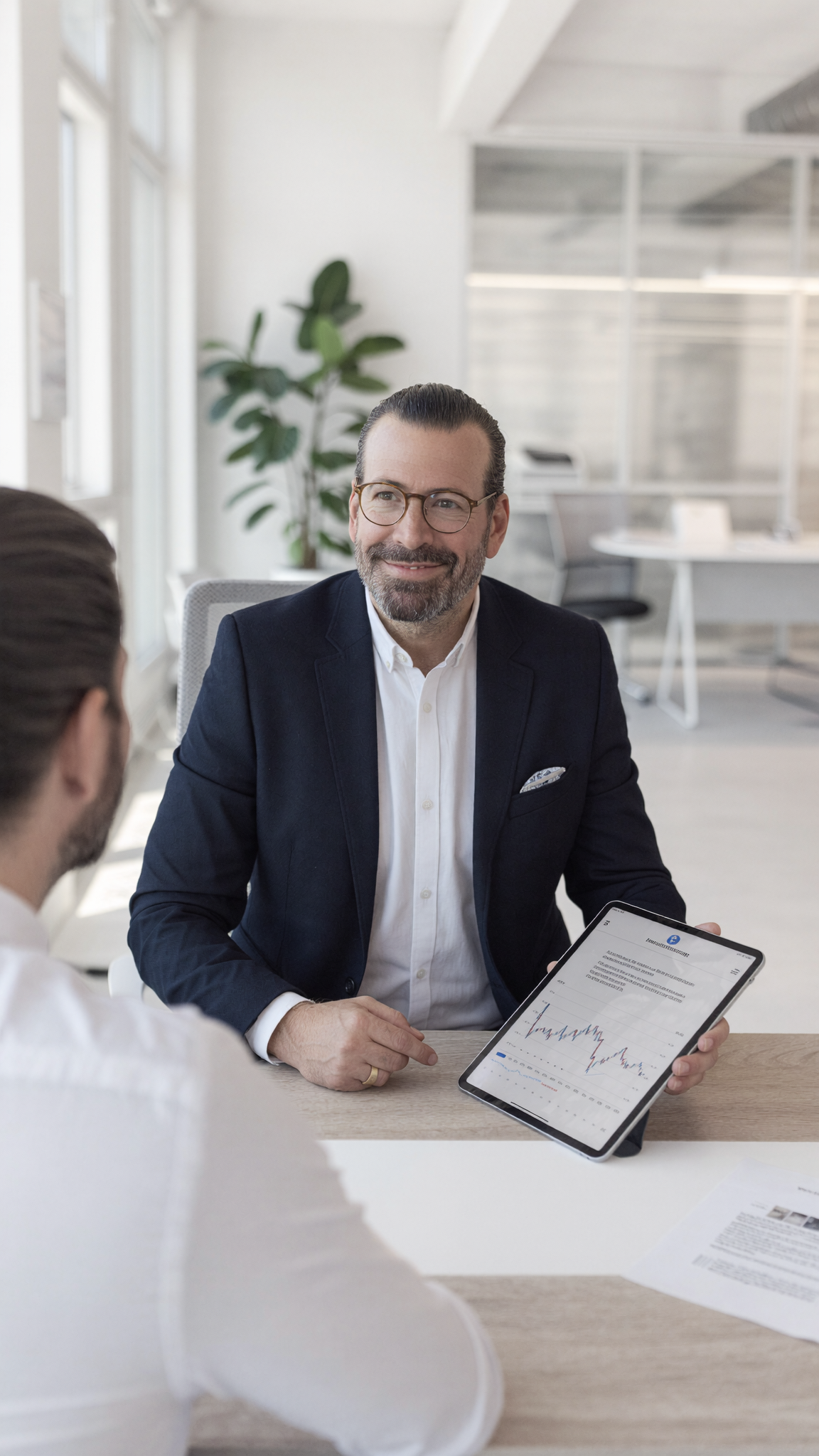 Consultant im Mandantengespräch: Berater zeigt einem Mandanten eine Auswertung auf dem Tablet